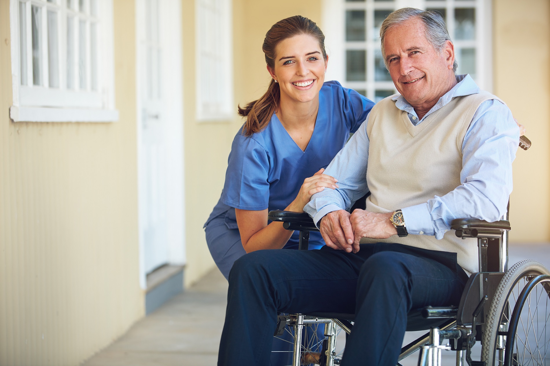 A nurse and an elderly man sitting on a chair.