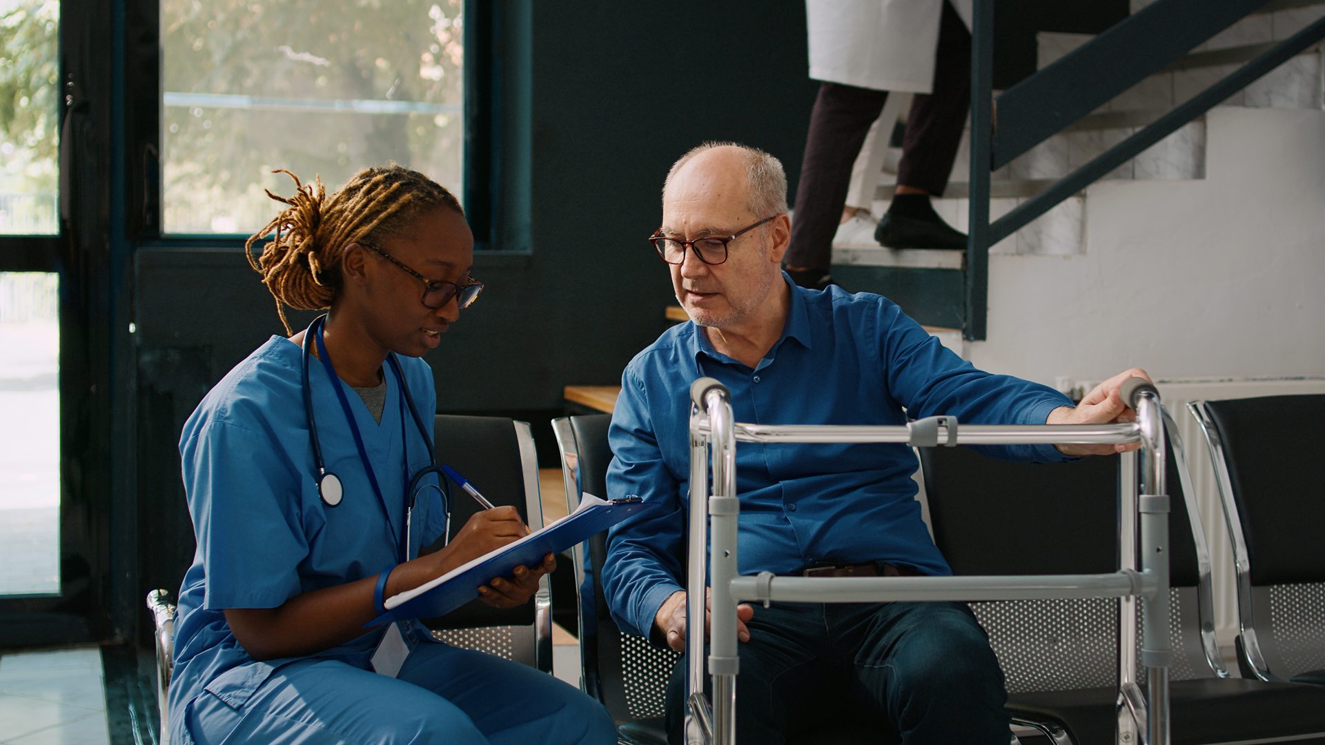 A nurse and an older man are talking to each other.