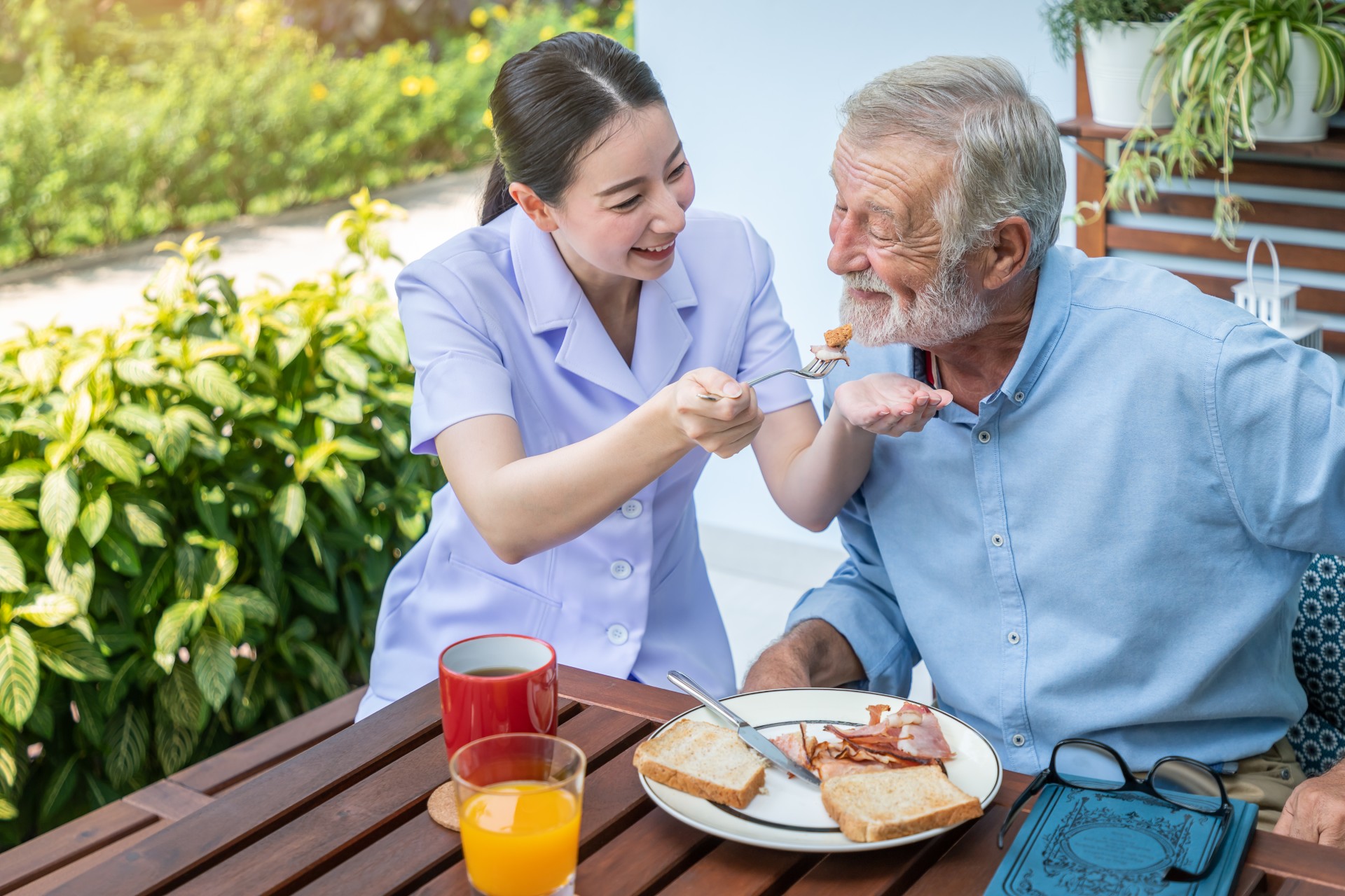 A woman feeding food to an older man.